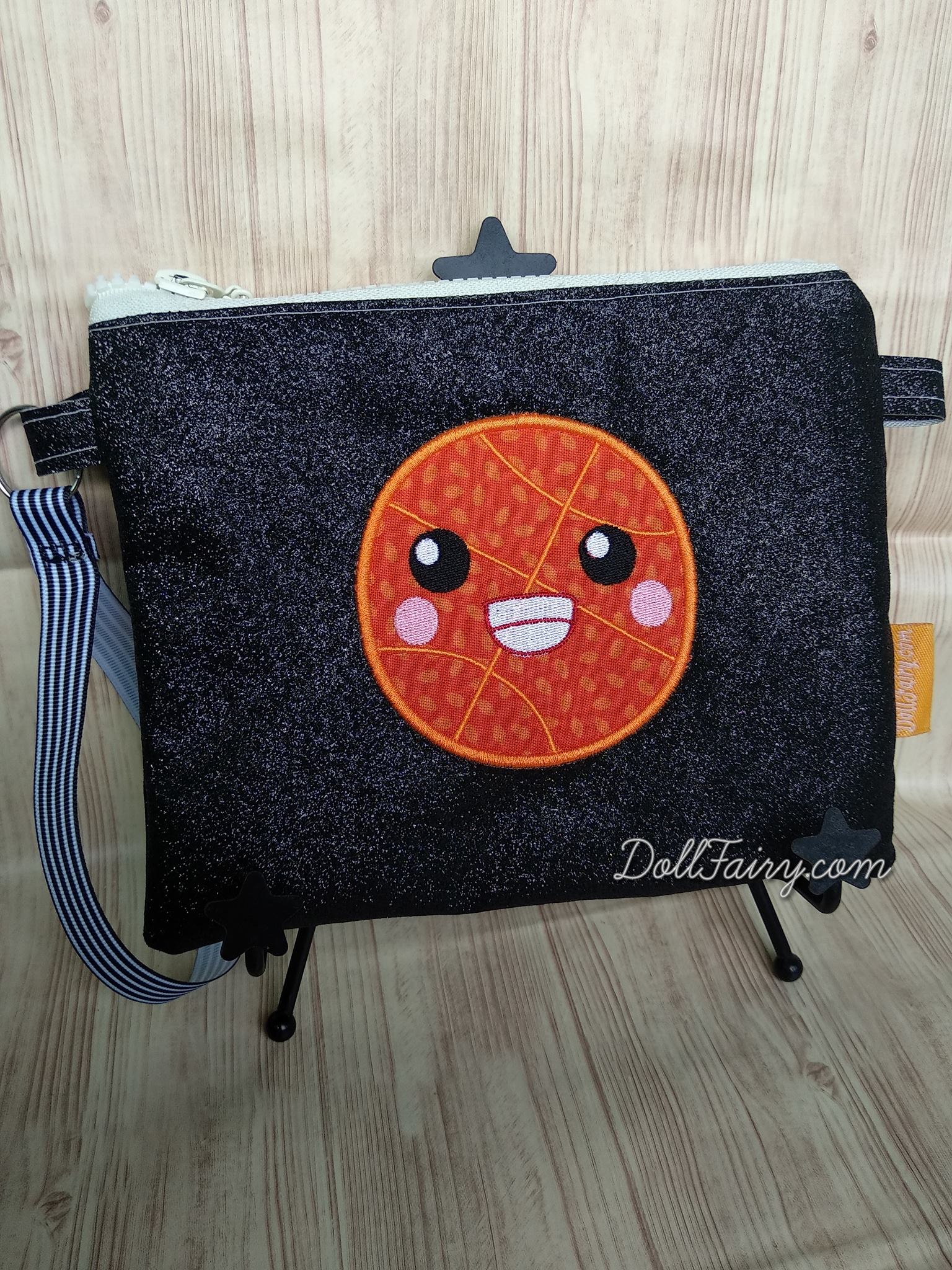 A smiley basketball on a black glitter pouch.